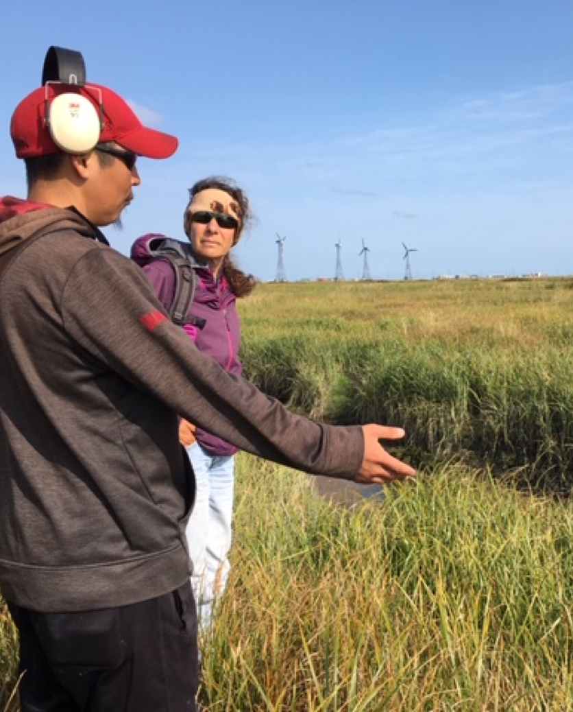 Man with headphones yalks to woman in a field of tall grass